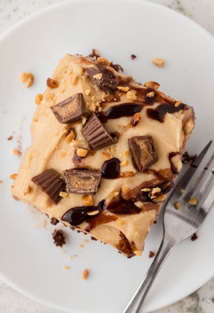 Top view of the slice of poke cake with peanut butter frosting, chocolate drizzle, and peanut butter cups.
