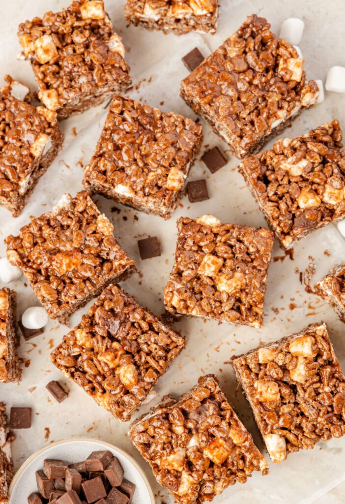 Krispie treats with chocolate chunks and marshmallows on a cutting board