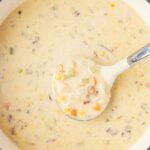 Top view of the soup pot of creamy chowder with a soup ladle in it.