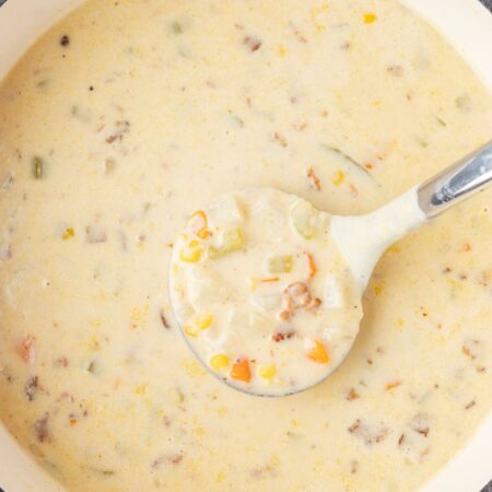 Top view of the soup pot of creamy chowder with a soup ladle in it.