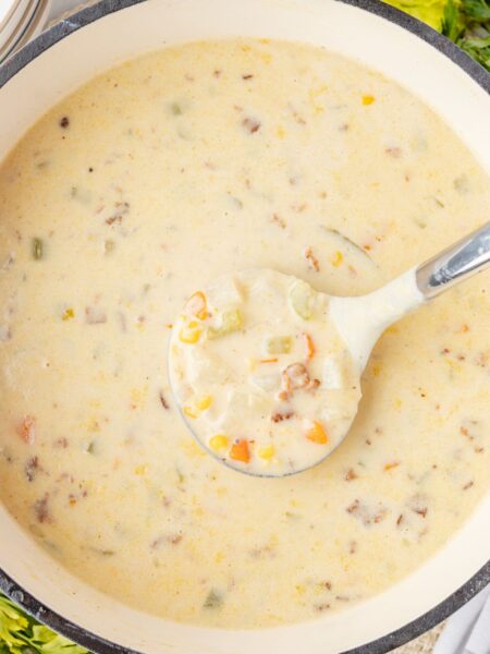 Top view of the soup pot of creamy chowder with a soup ladle in it.