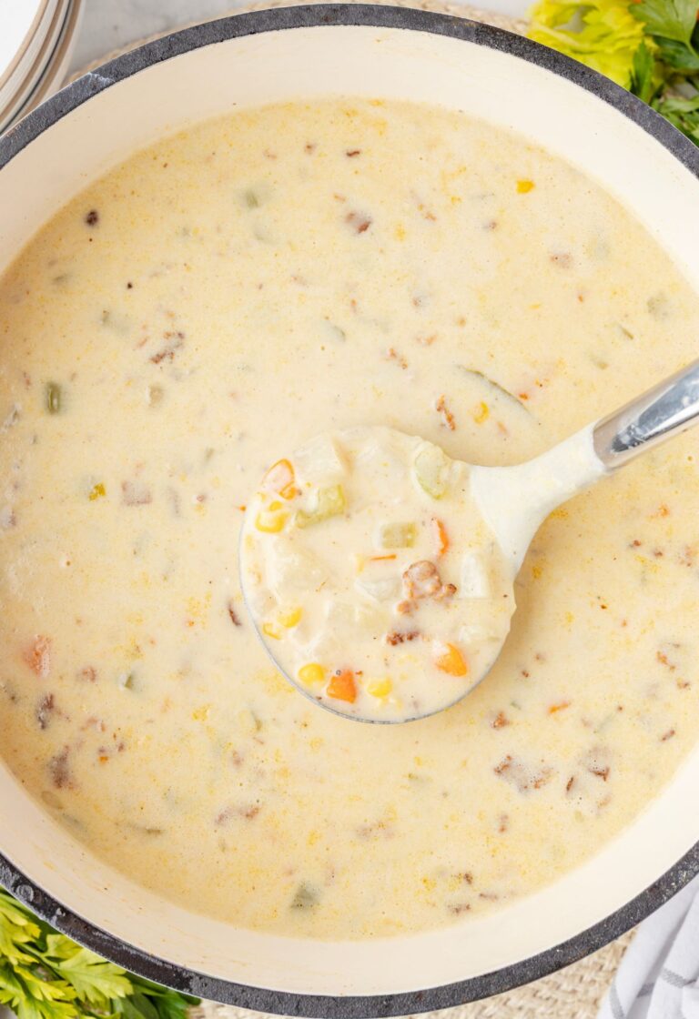 Top view of the soup pot of creamy chowder with a soup ladle in it.