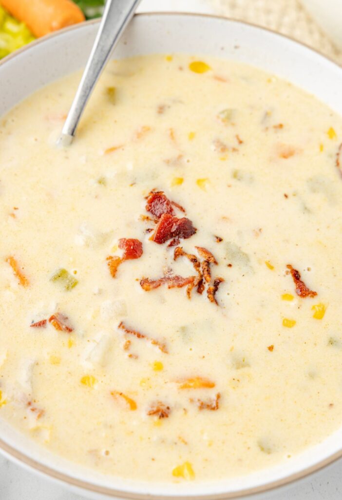 A white bowl with chowder in it and a spoon