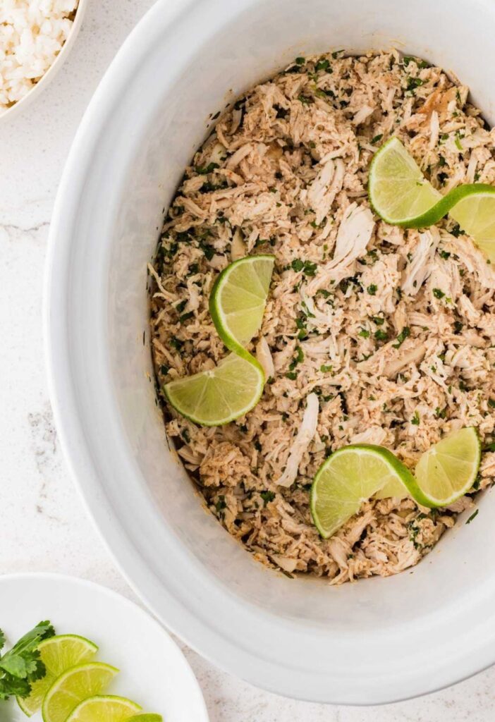 Inside of the crockpot with the cooked shredded cilantro lime chicken in it.
