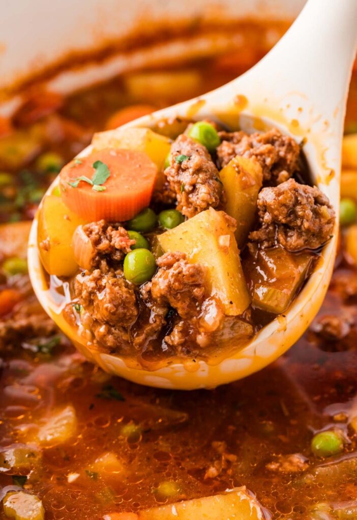 A ladle with some ground beef stew on it.