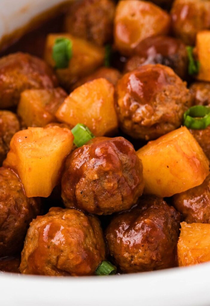Close up of the baked meatballs with barbecue sauce and pineapple chunks.