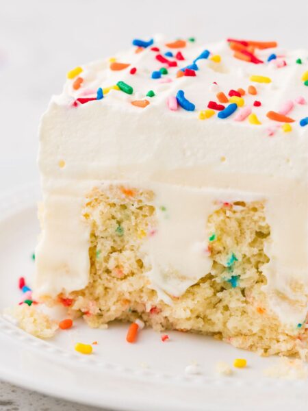A slice of poke cake on a white plate