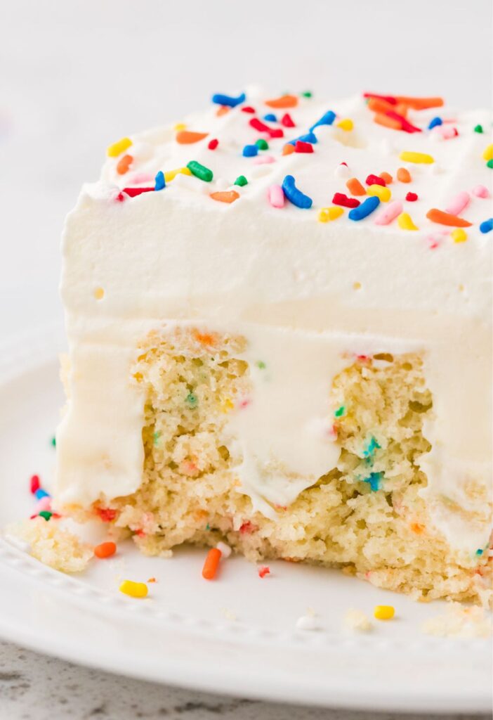 A slice of poke cake on a white plate