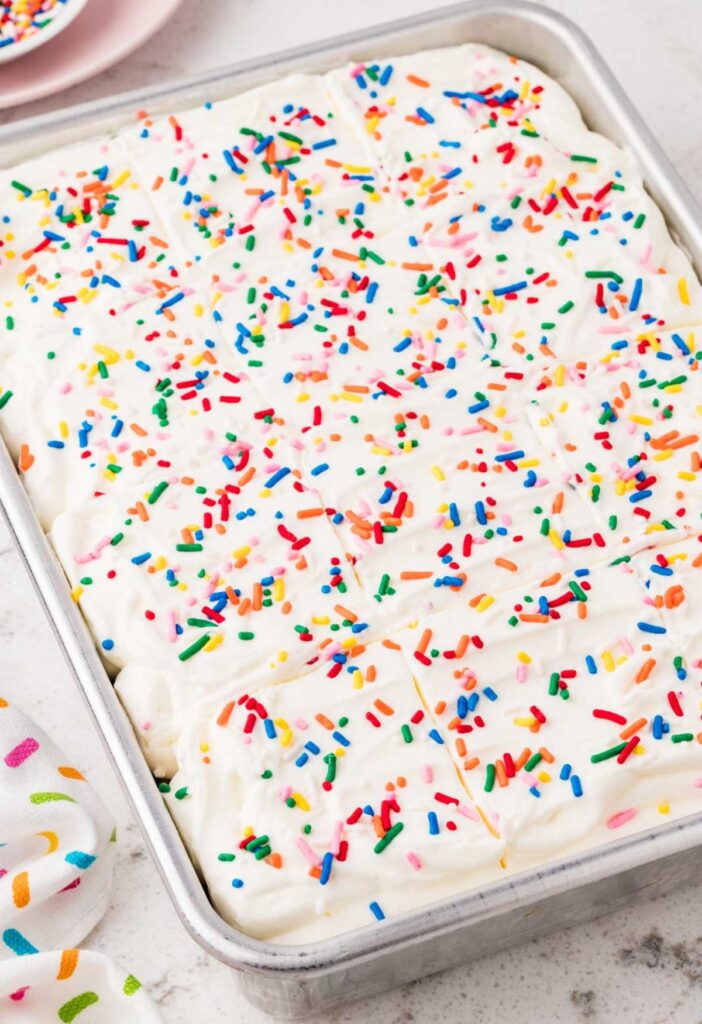 A cake pan of the poke cake with sprinkles on top.