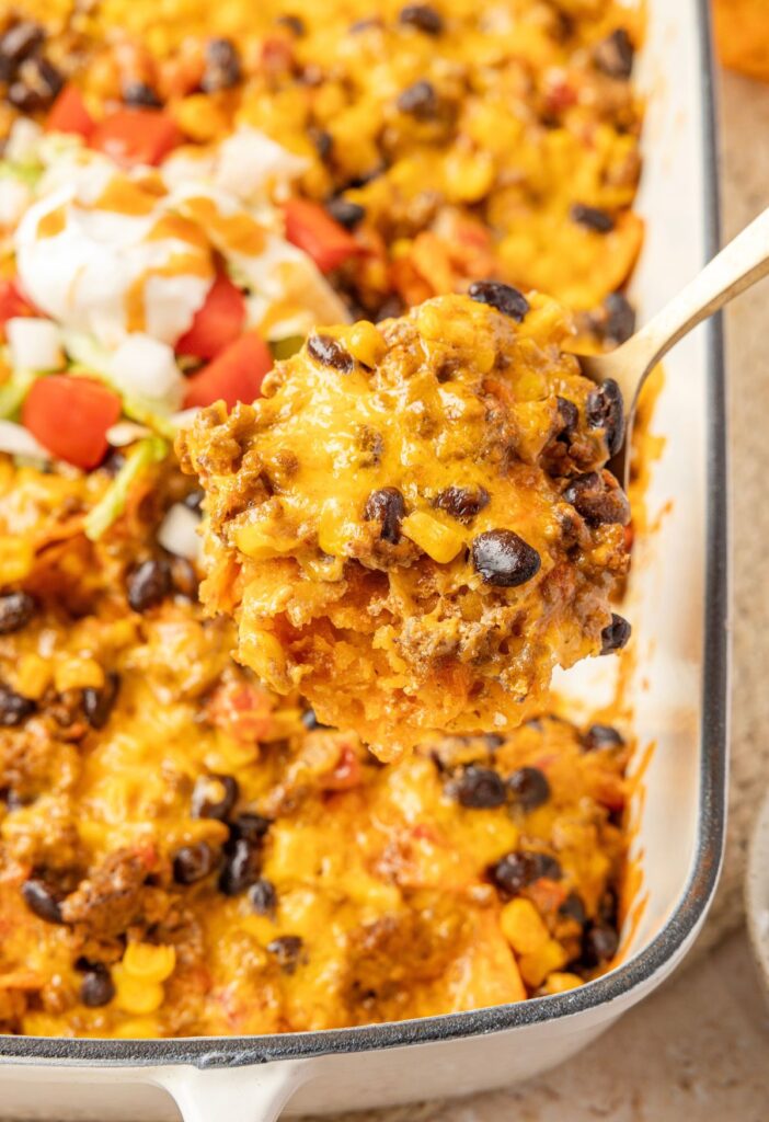 A spoon scooping up some casserole from the Doritos casserole with ground beef.