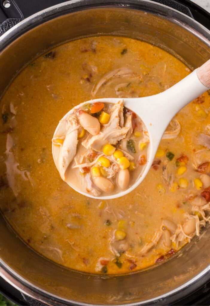 Scoop of the chicken chili above the instant pot.