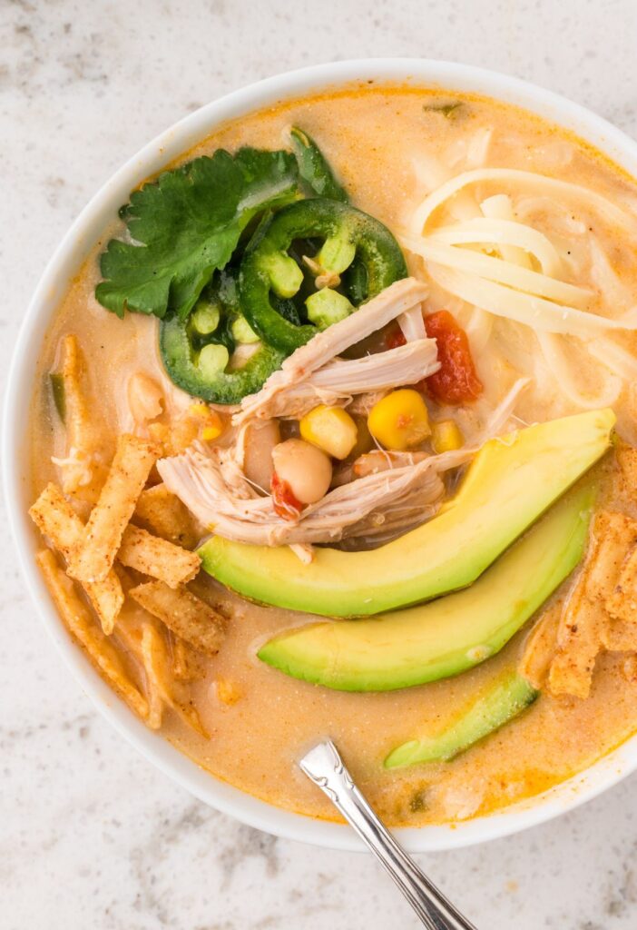 Bowl of white chicken chili with a spoon inside of it.