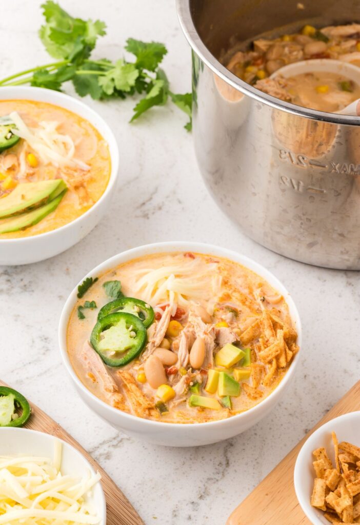 overhead picture of the instant pot and a white serving bowl with some white chicken chili in it.