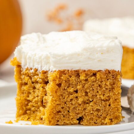 A cream cheese frosted pumpkin bar sitting on a plate.