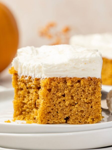 A cream cheese frosted pumpkin bar sitting on a plate.