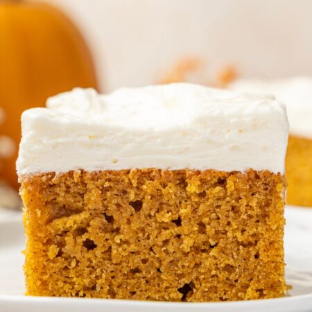 Piece of pumpkin bar on a stack of white plates.