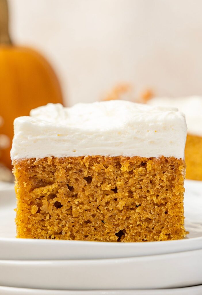 Piece of pumpkin bar on a stack of white plates.
