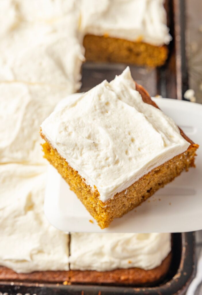 A spatula holding a square of the pumpkin bars above the pan of them.
