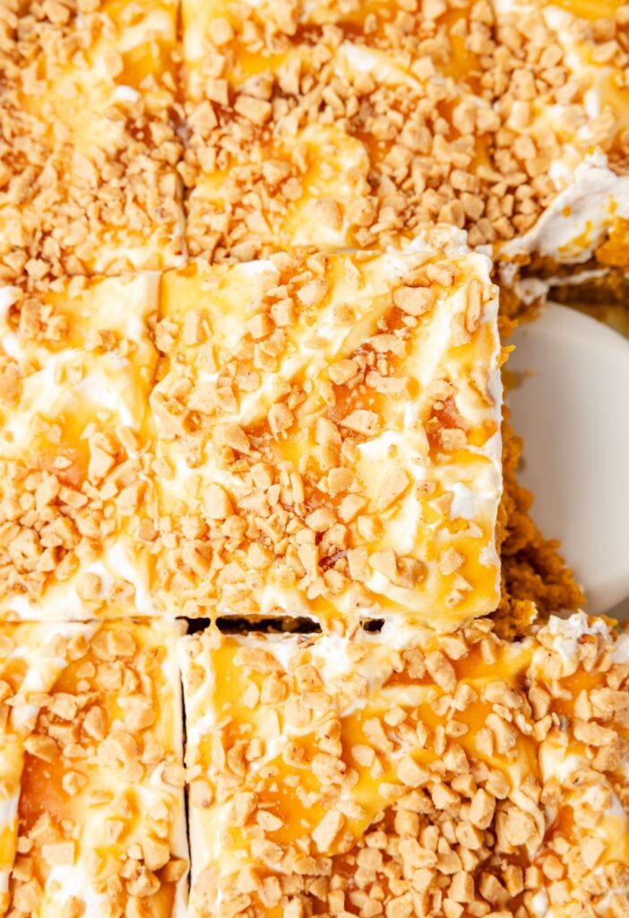 A pan of the pumpkin poke cake with a serving spatula inside of it