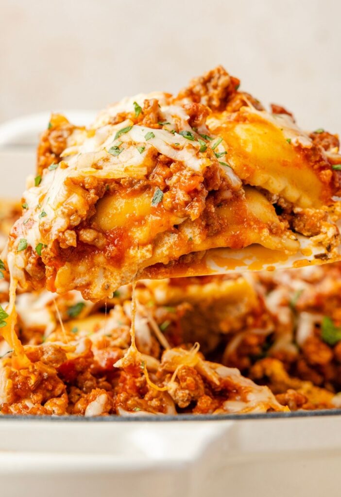 A spatula holding a serving of the ravioli lasagna above the casserole