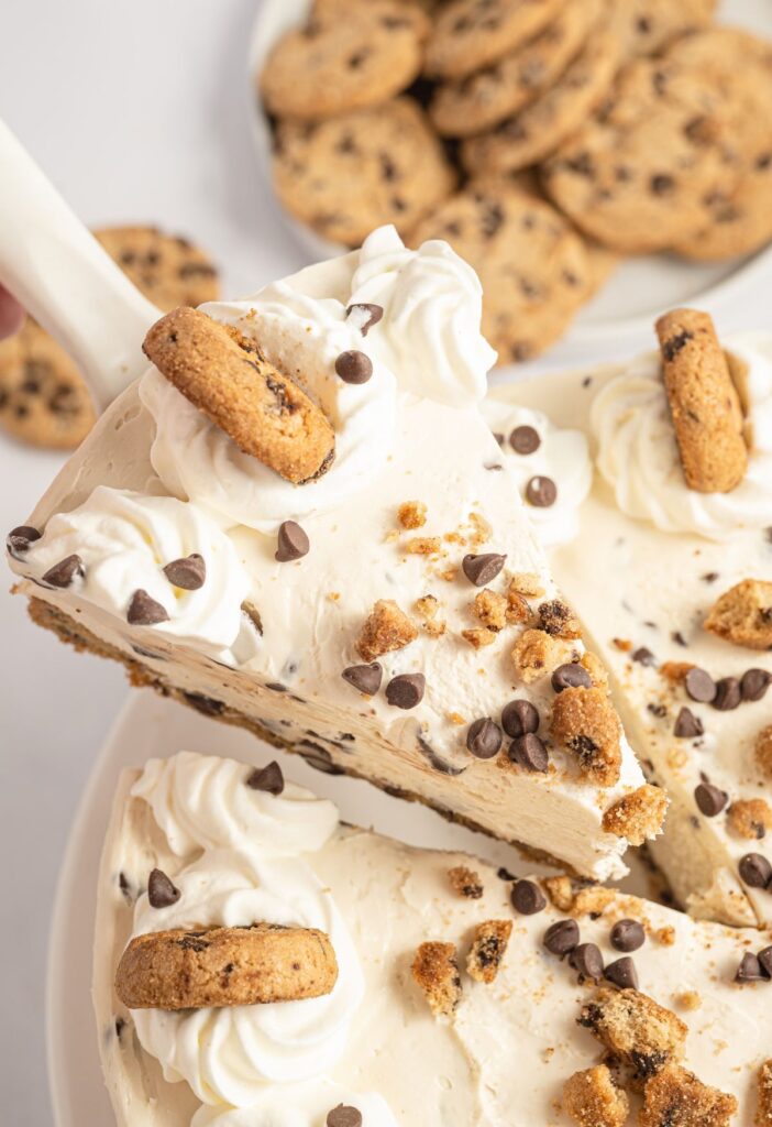 A spatula with a slice of the no bake cheesecake on it with chocolate chip cookies.