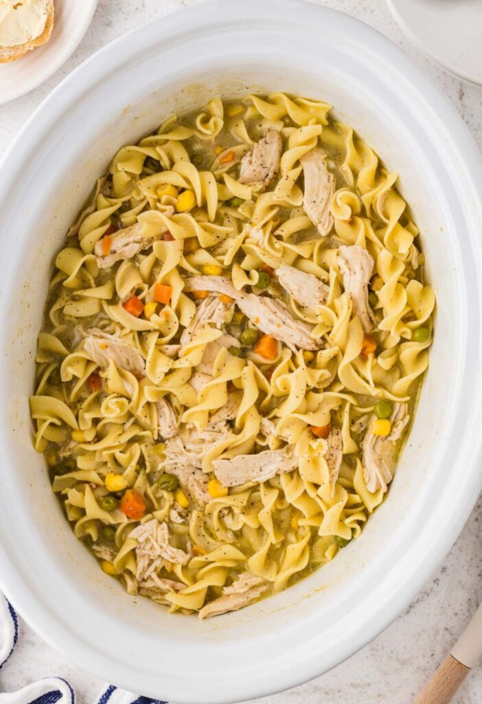 View of the crock pot with the cooked chicken pot pie noodles inside ready to serve.