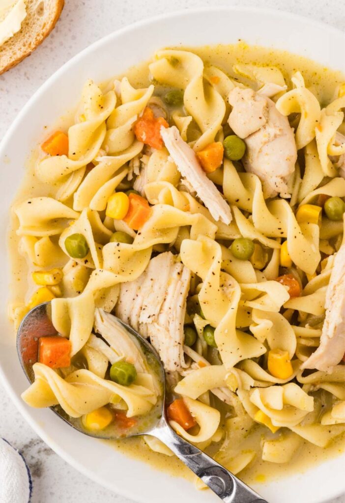 A plate of the pot pie noodles with chicken and a spoon.