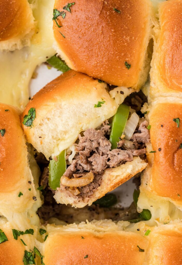 philly cheesesteak sliders, baked and ready to serve with one sideways to see the middle