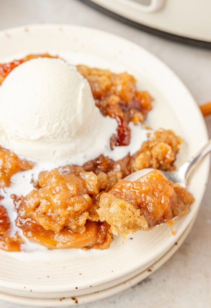 A serving of apple crumble on a white plate with ice cream
