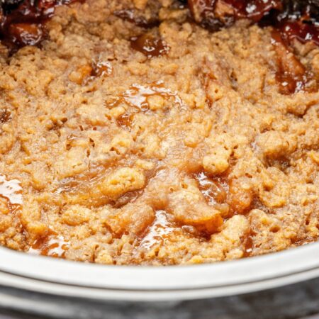 The slow cooker with the baked apple crumble inside of it