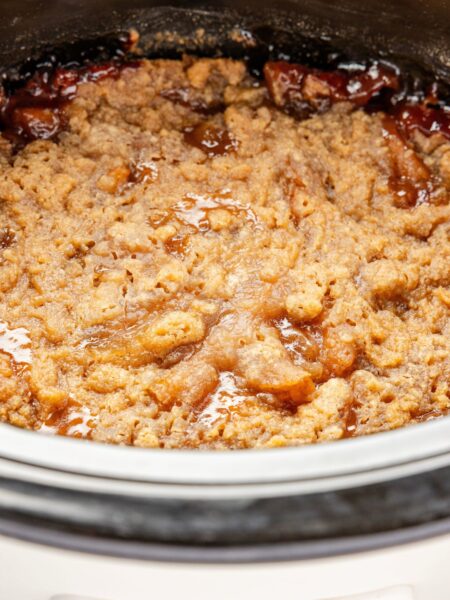 The slow cooker with the baked apple crumble inside of it
