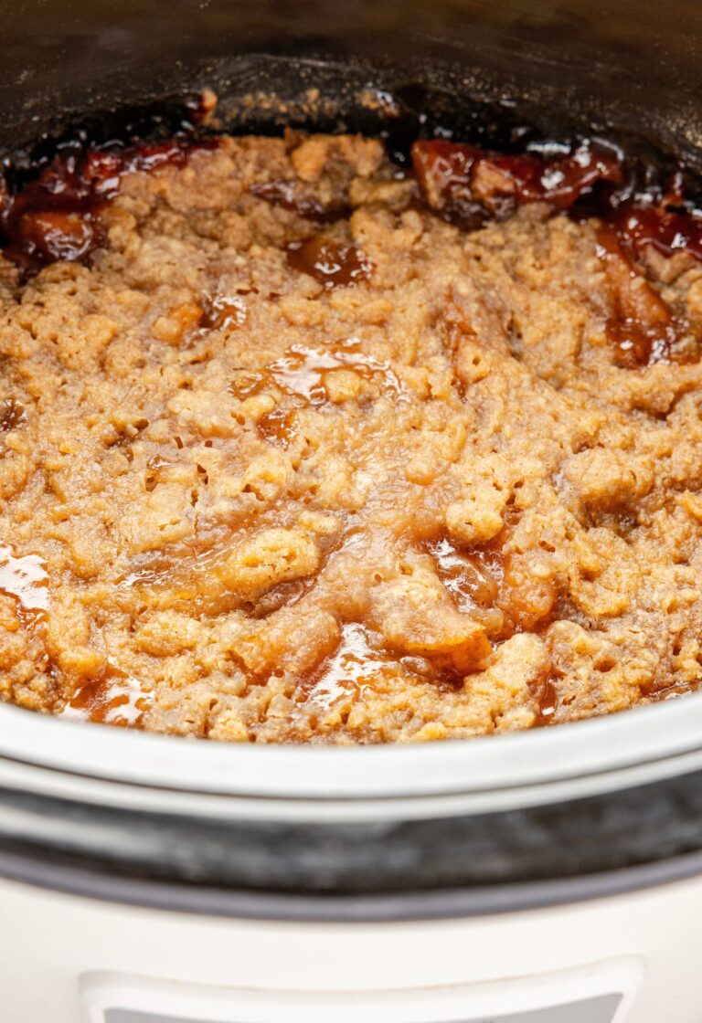 The slow cooker with the baked apple crumble inside of it