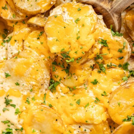 Inside of the slow cooker with the cooked scalloped potatoes covered in melted cheese.