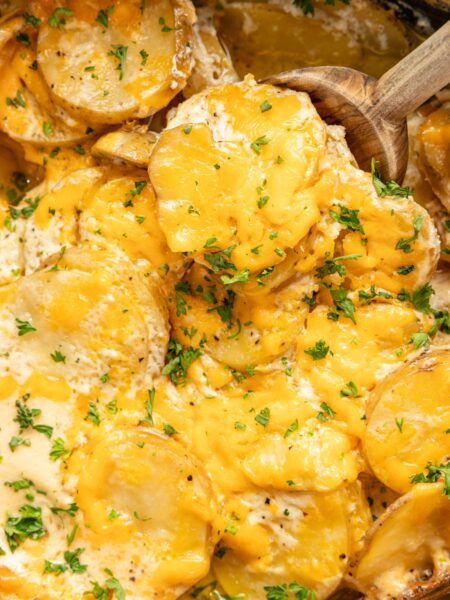 Inside of the slow cooker with the cooked scalloped potatoes covered in melted cheese.