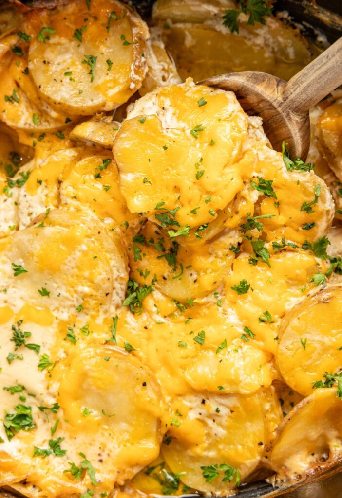 Inside of the slow cooker with the cooked scalloped potatoes covered in melted cheese.