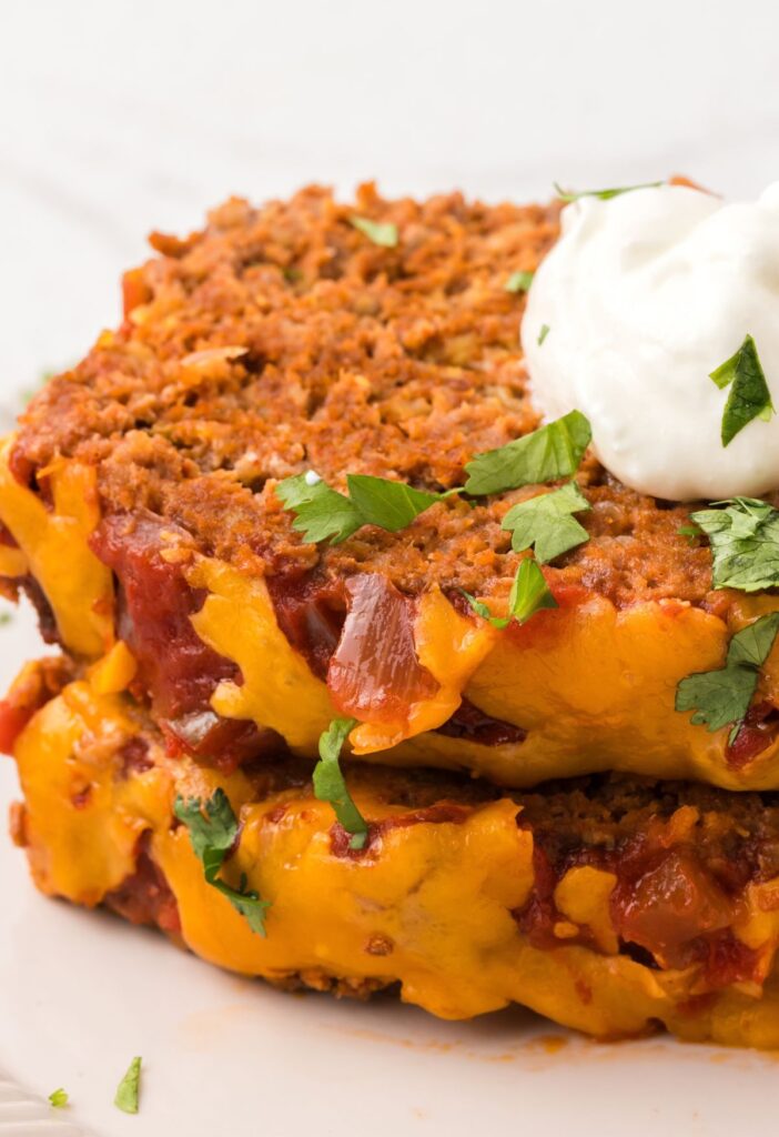 A stack of two meatloaf slices topped with sour cream and cilantro.