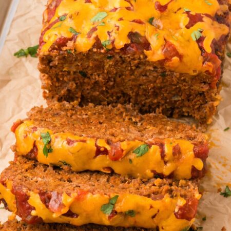 The meatloaf cut into slices sitting on parchment paper.