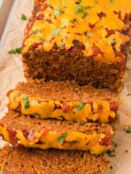 The meatloaf cut into slices sitting on parchment paper.