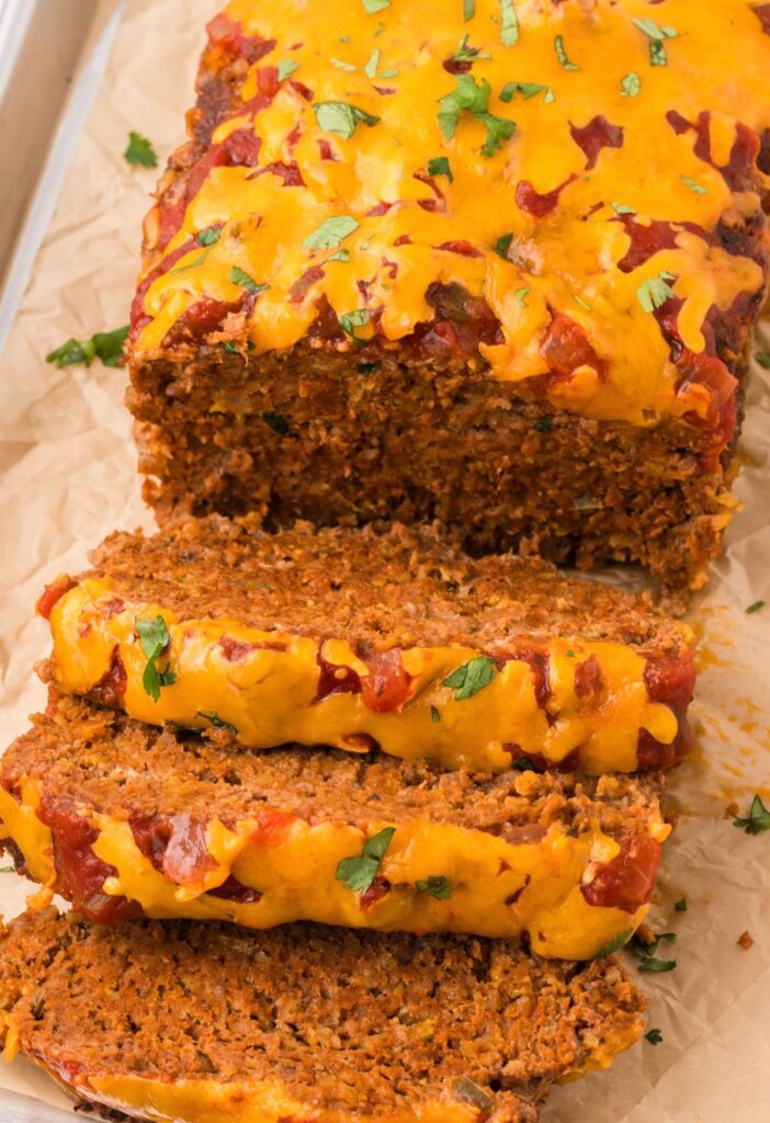 The meatloaf cut into slices sitting on parchment paper.